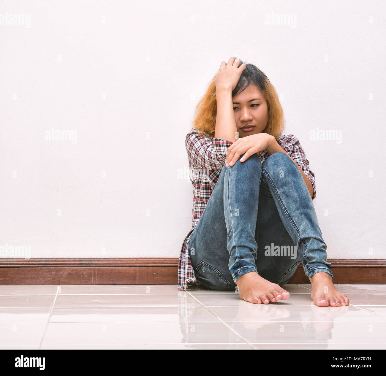 young hipster woman, sad, long-haired  sitting hugging legs. Stock Photo