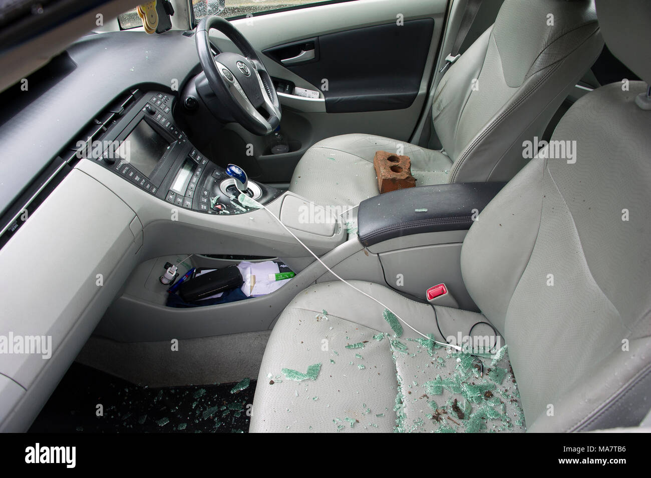 A car recently broken into with offending brick visible on driver seat
