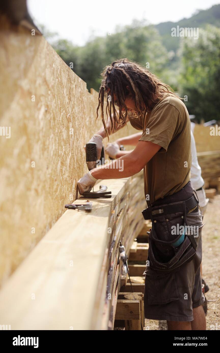 4 in a series of 32, building a timber footbridge. Workers fix offset layers of timber with glue and screws into the arch shape  Construction of a scr Stock Photo