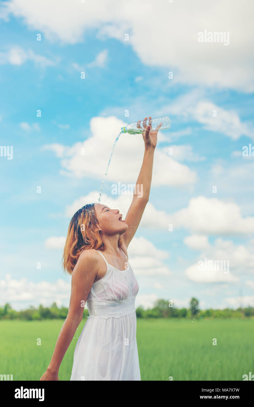 Young woman in park pours over a face for freshing at grassland enjoy and happy life. Stock Photo