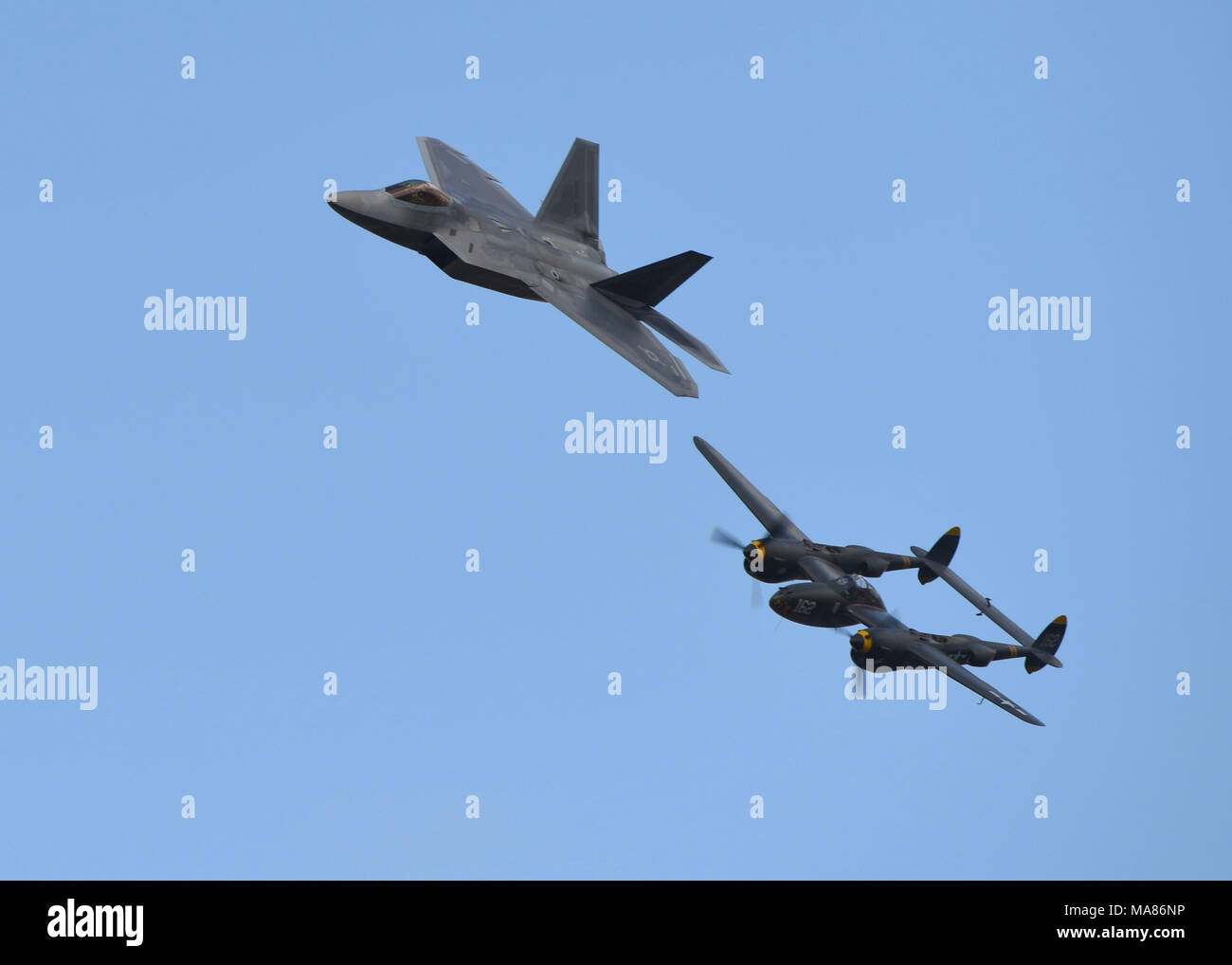A U.S. Air Force F-22 Raptor flies alongside a P-38 Lightening during a Heritage Flight at the Los Angeles County Air Show in Lancaster, Calif., March 24, 2018. Heritage Flight educates those about the fighter aircraft from World War II, Korea and Vietnam while honoring veterans who flew them. (U.S. Air Force photo by Senior Airman Kaylee Dubois) Stock Photo