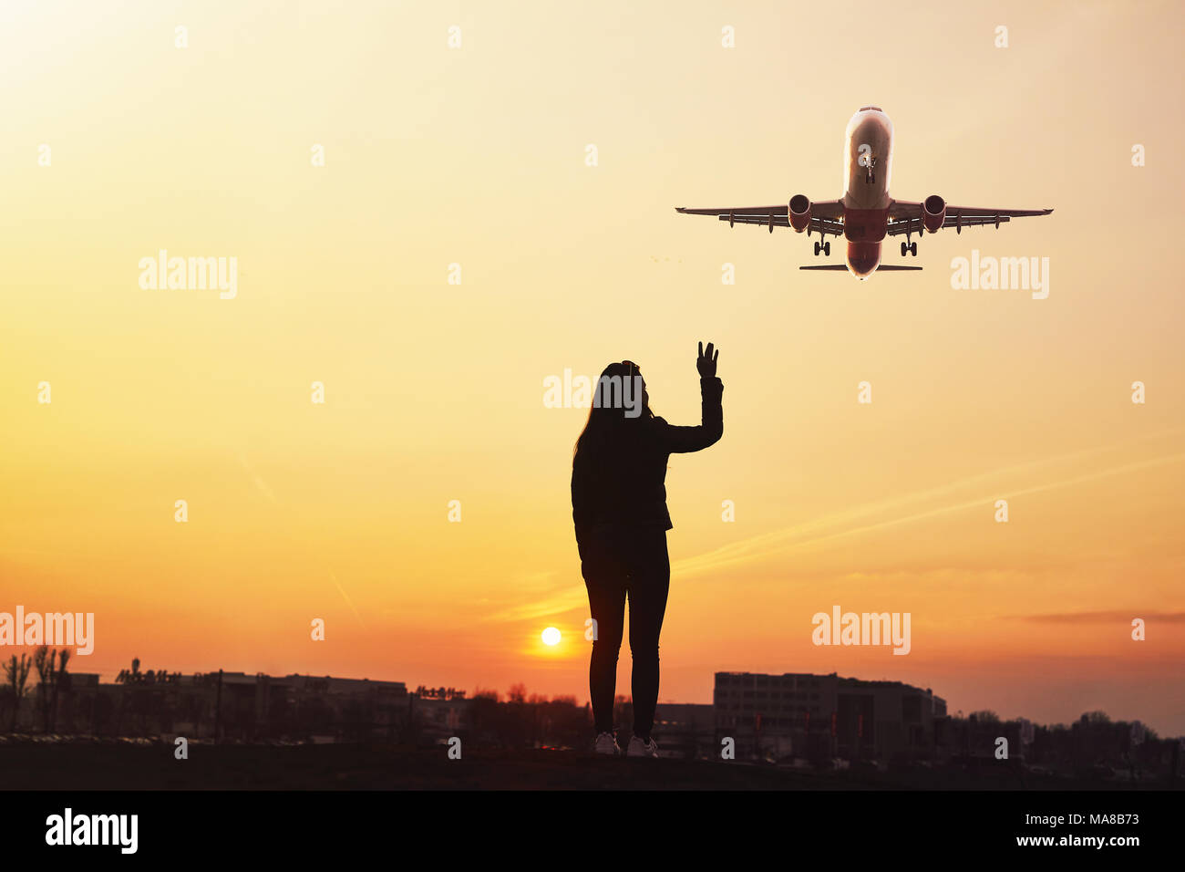 Girl wave to the plane with sunset background Stock Photo - Alamy