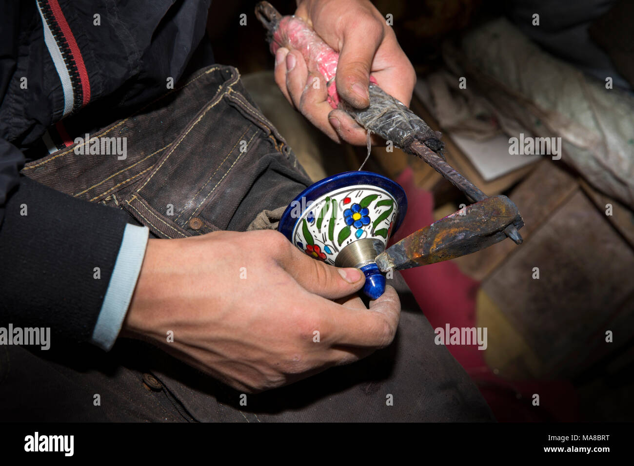 Morocco, Fes, Quartier des Potiers, Pottery, worker soldering silver decoration onto pot lid Stock Photo