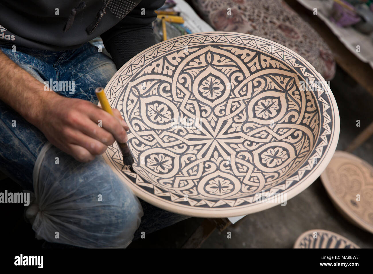 Morocco, Fes, Quartier des Potiers, Pottery, worker hand decorating geometric patterned dish Stock Photo