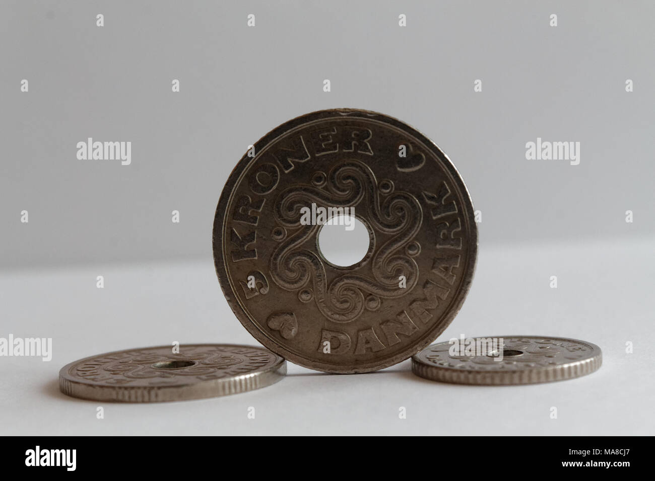 Three Denmark coins lie on isolated white background Front coin Denomination is 5 krone (crown) - back side Stock Photo