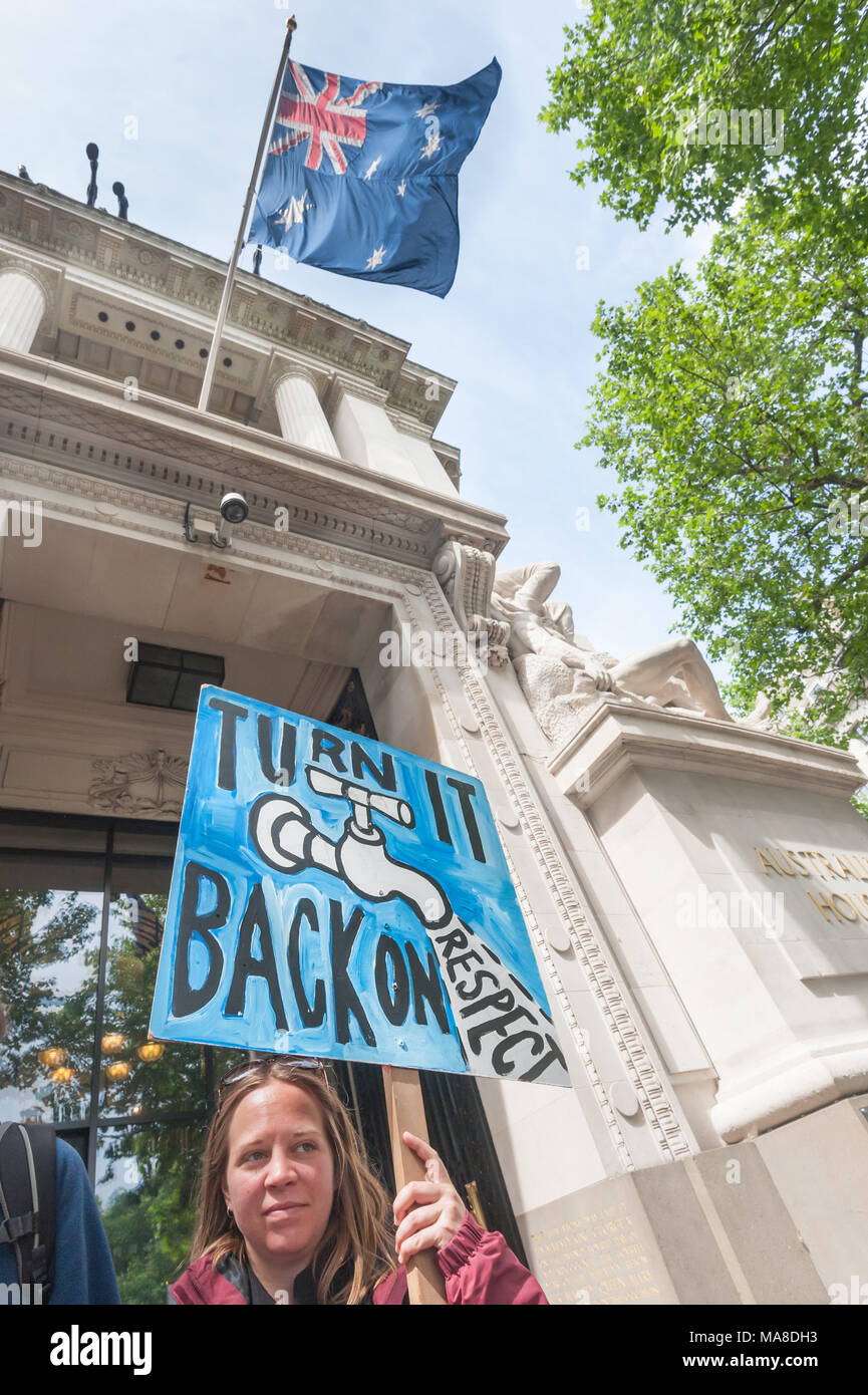 A woman holds a placard showing a tap and calling on the Australian government to turn back on their respect for Aborigine rights under the Australian flag flying on Australia House, London. Stock Photo