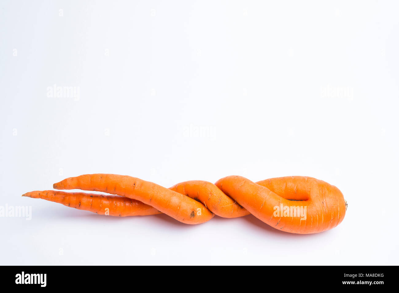 carrots of unusual shape lies on a white background Stock Photo