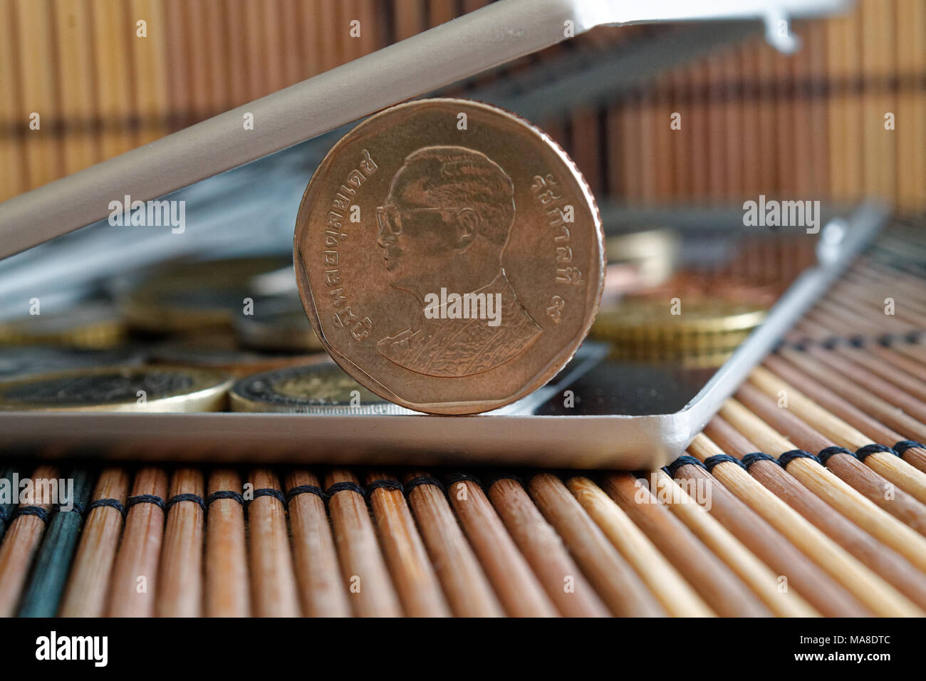 Pile of Thai coins in mirror reflect wallet lies on wooden bamboo table ...