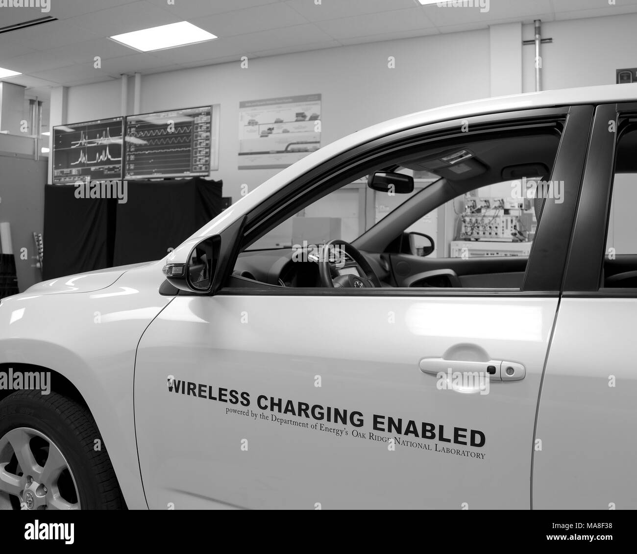 Side view of a white, Toyota brand, electric car, parked in a laboratory, above a 20-kilowatt, wireless fast-charging system, produced at Oak Ridge National Laboratory (ORNL) image courtesy of the US Department of Energy, 2016. () Stock Photo