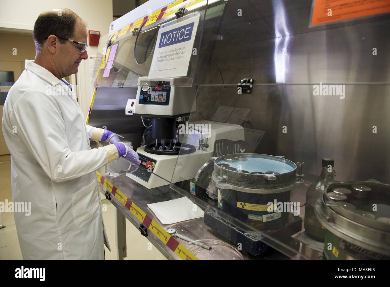 Male researcher uses a polarized light optical microscope, in a lab