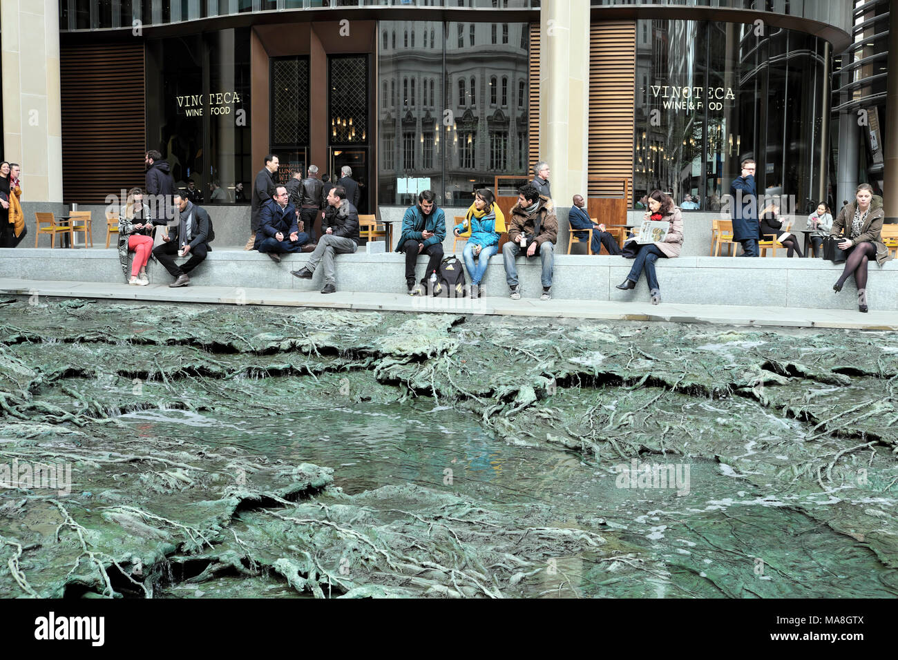 People sitting by 'Forgotten Streams' sculpture by artist Cristina Iglesias at the Bloomberg Headquarters building in City of London UK   KATHY DEWITT Stock Photo