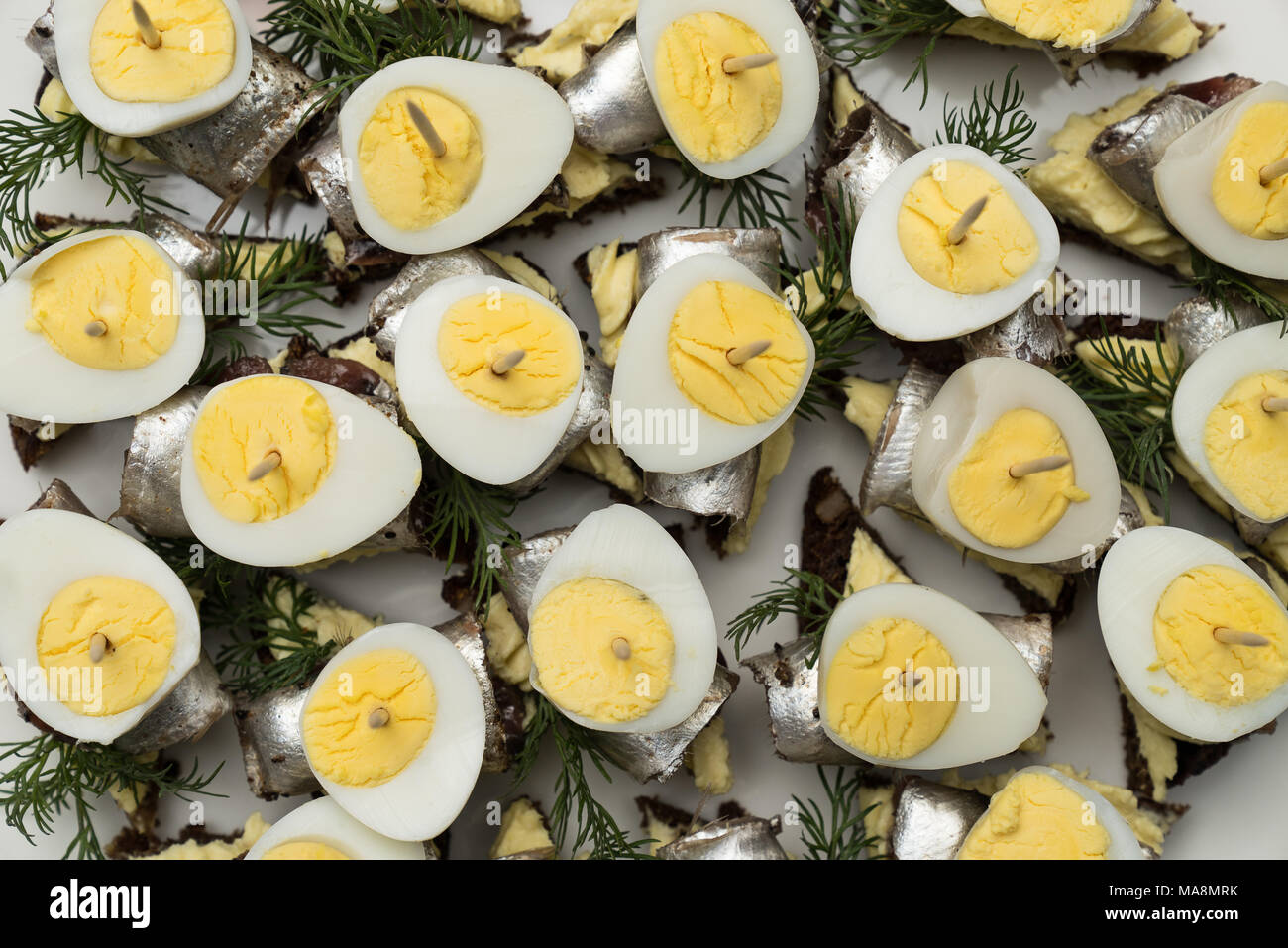 Mini sandwich with salt sprat and sliced boiled quail egg on the slice