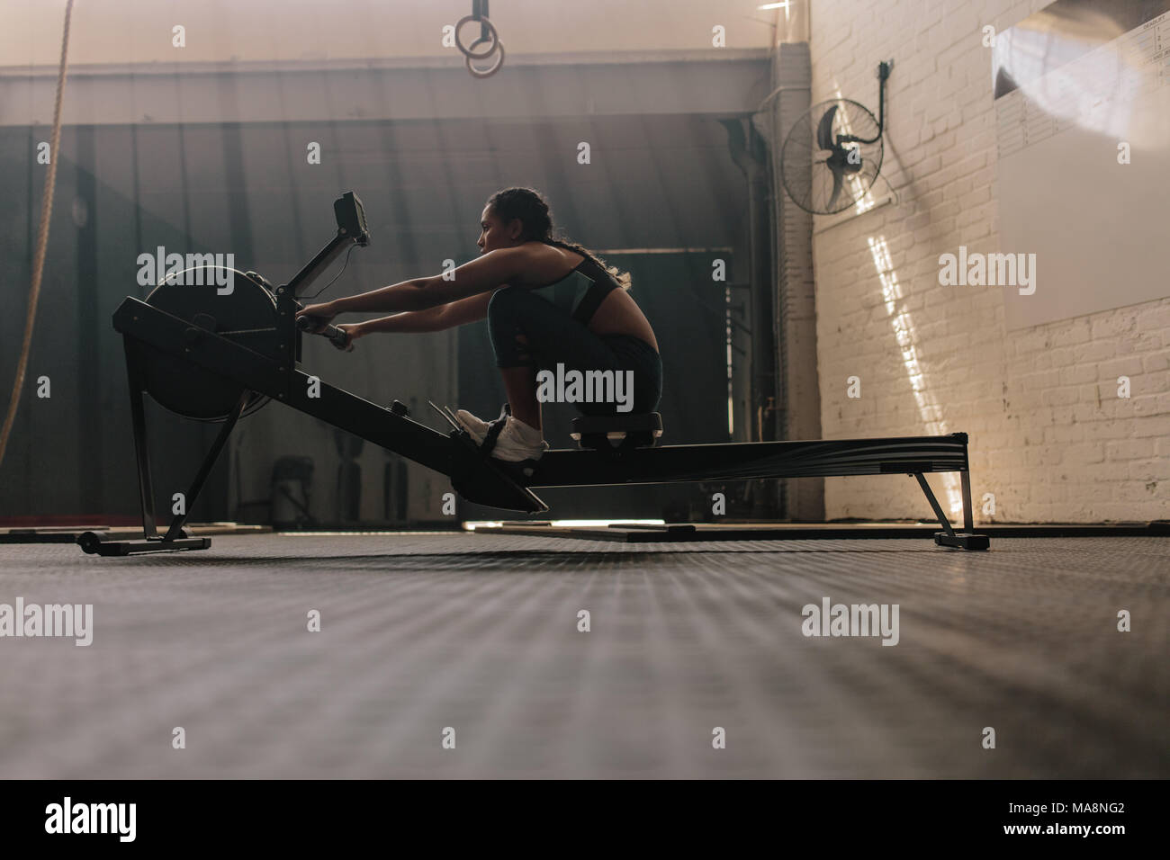 Female athlete using rowing machine. Fit woman doing cardio workout in ...
