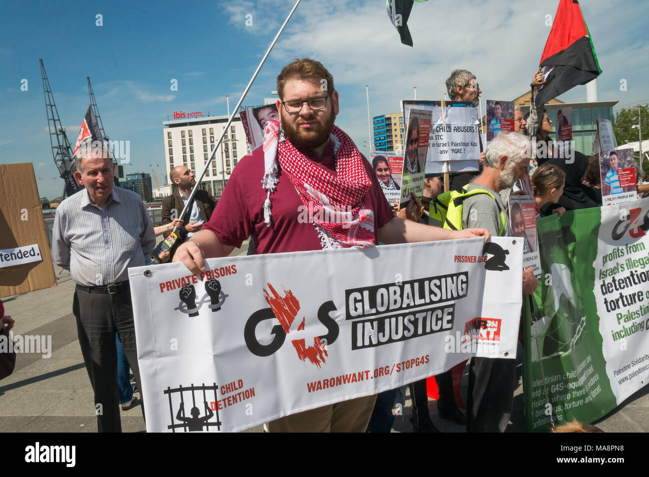A man holds a War on Want banner 'G4S Globalising Injustice' at the Stop G4S protest outside G4S AGM at Excel London. Stock Photo