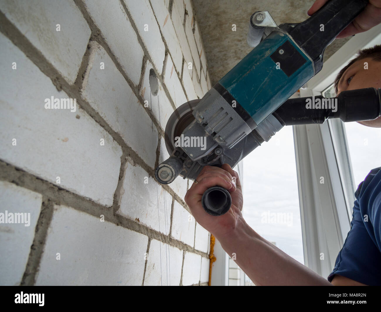 Voronezh, Russia - May 13, 2017: Making a groove in the wall with an angle grinder Stock Photo