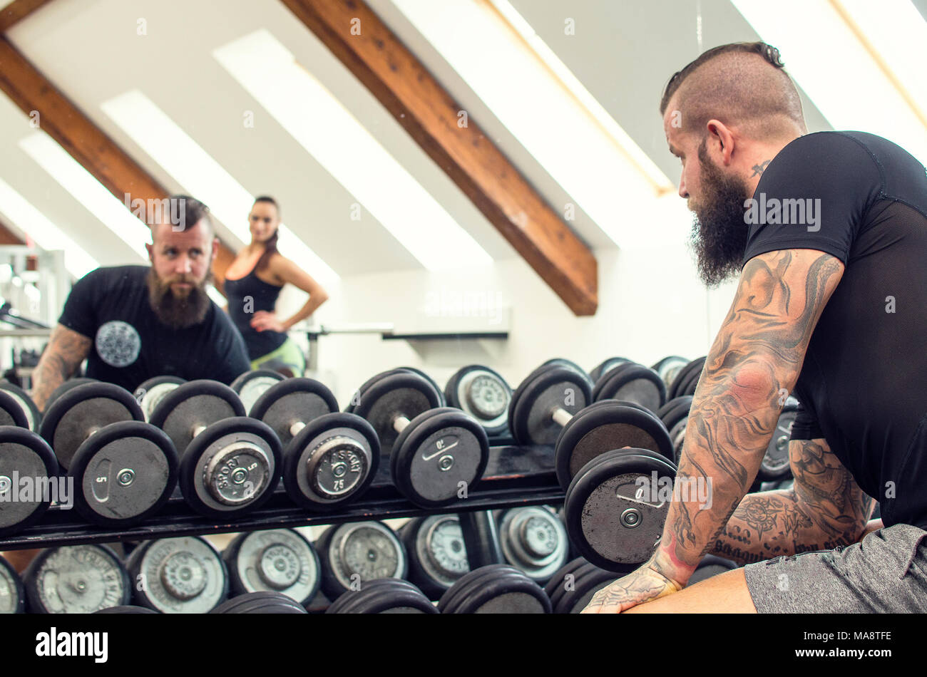 Beard man with long hair exercising with dumbbells. Stock Photo