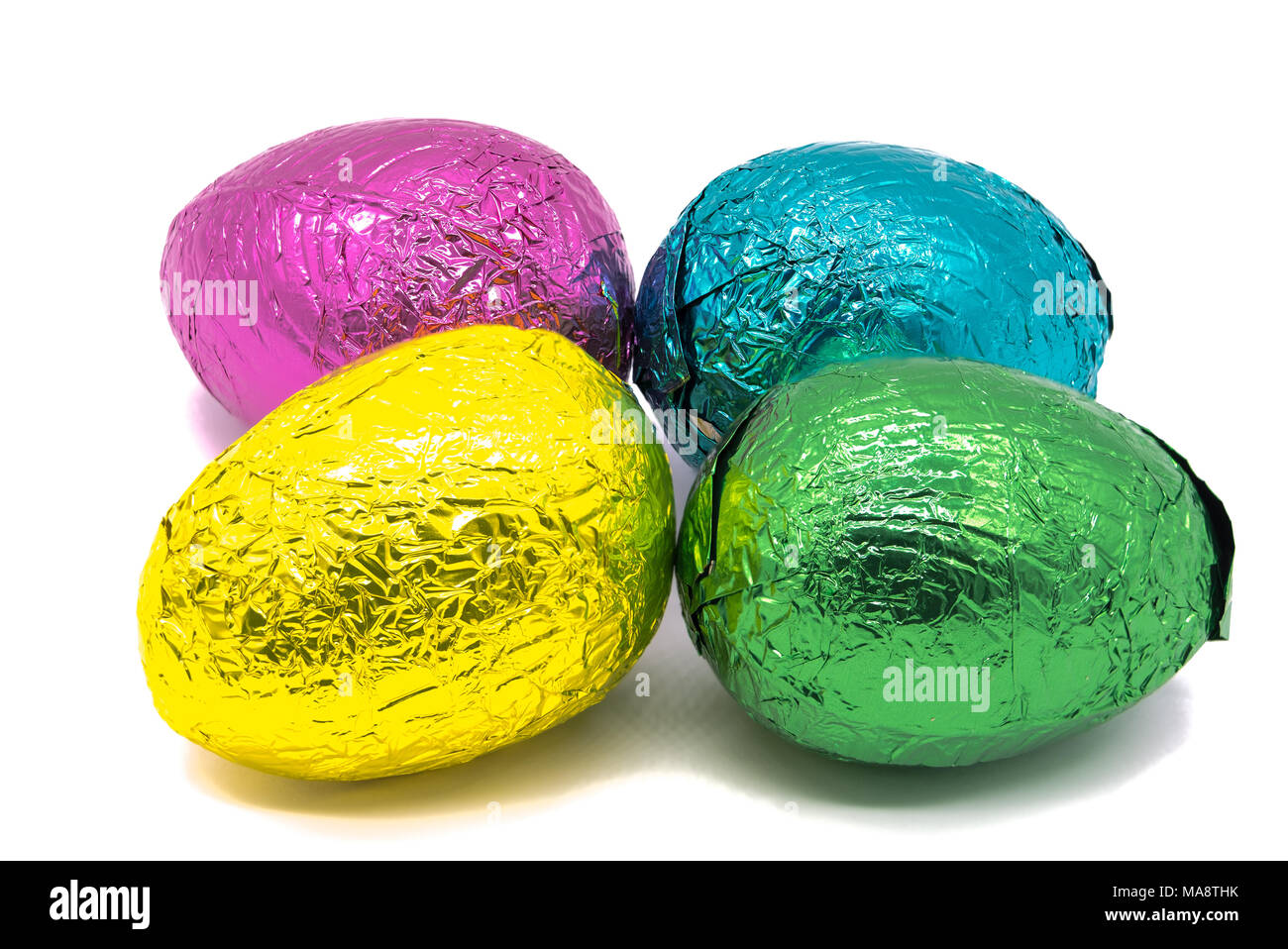 Four Colourful Foil Wrapped Easter Eggs on a plain white background Stock Photo