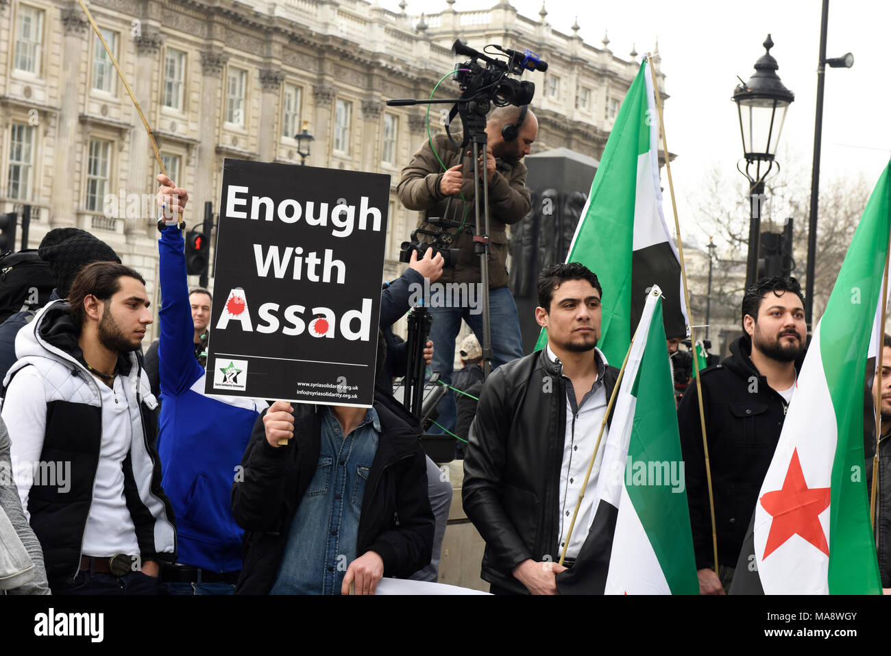 Syrian protesters holding a placard reading: 'Enough With Assad' outside the Downing Street in London, UK. Stock Photo