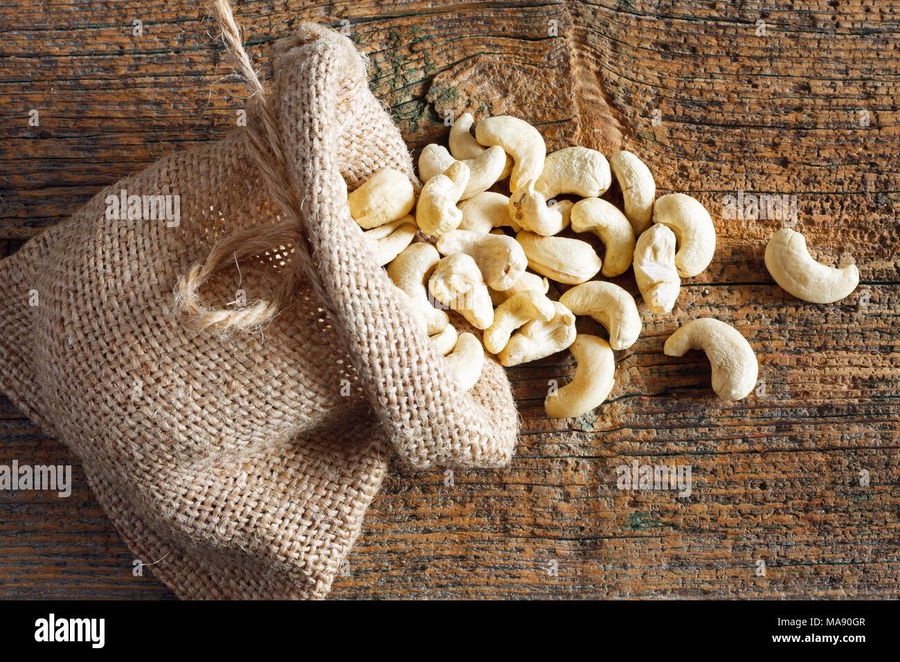 Cashew nuts in small sack on wooden background Stock Photo