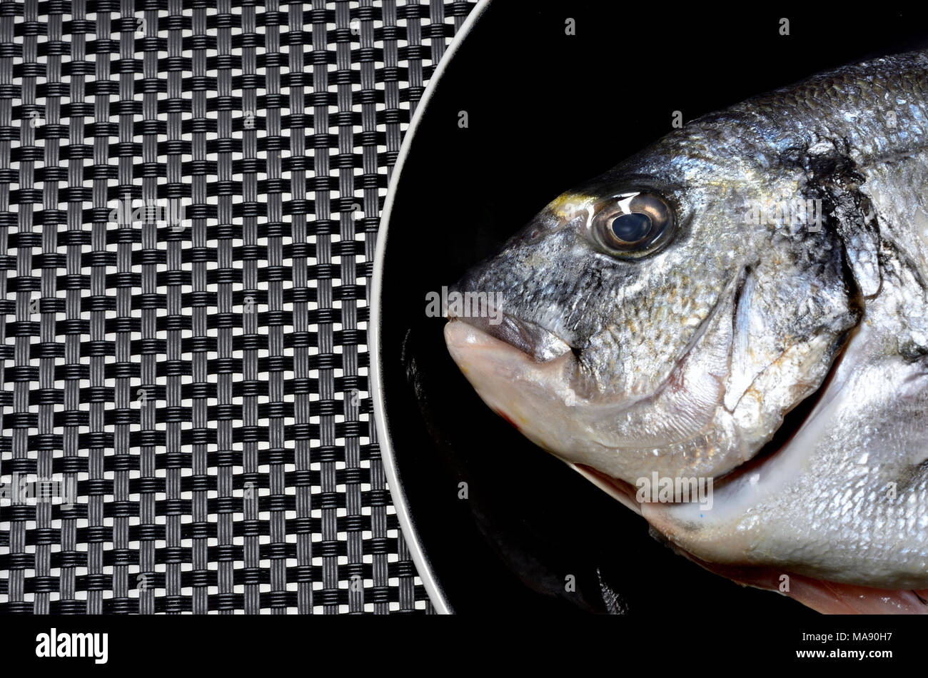 Fresh uncooked Sea Bass on a black plate Stock Photo