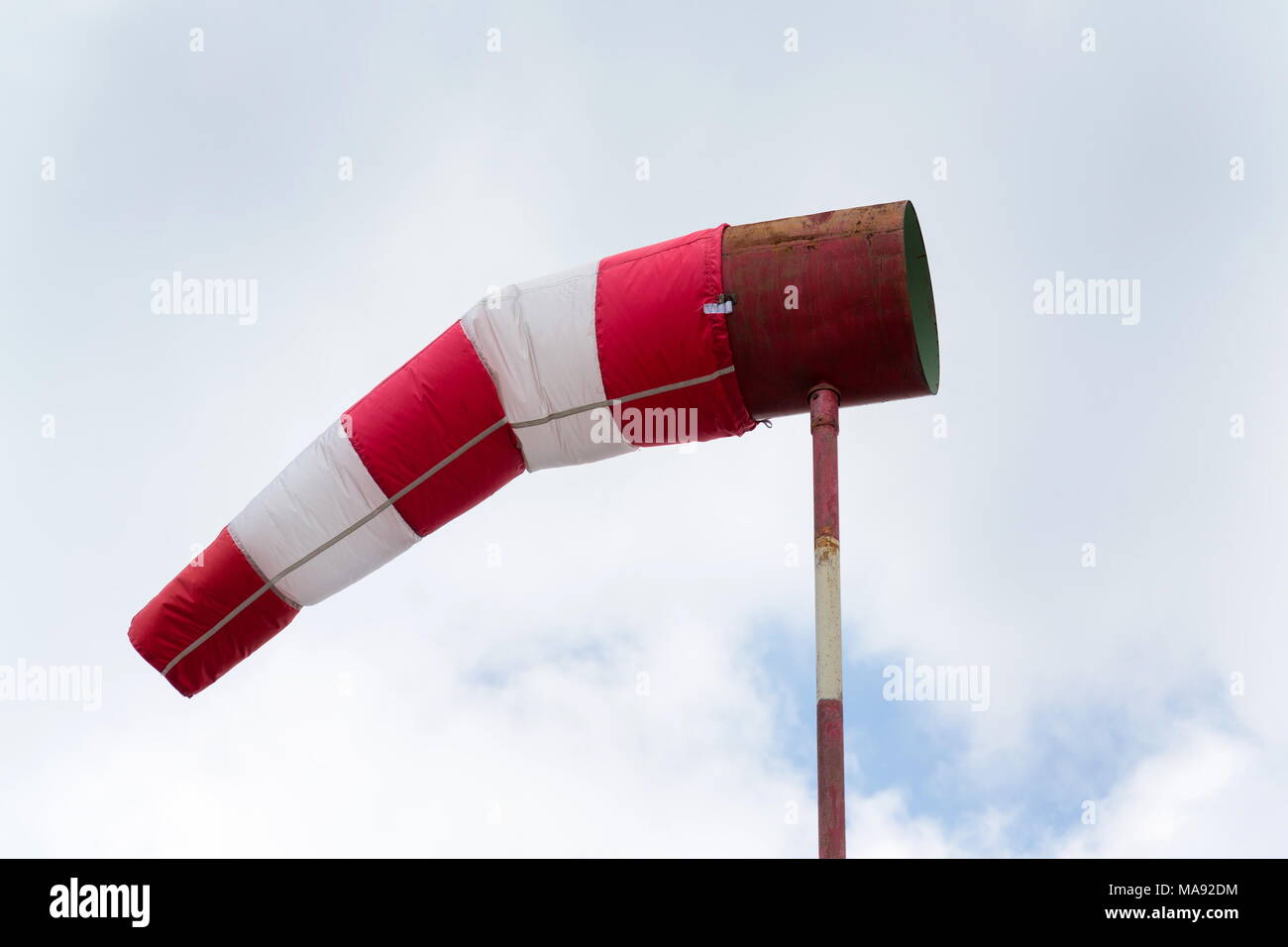 Red and white windsock, dramatic clouds, windy weather forecast concept Stock Photo
