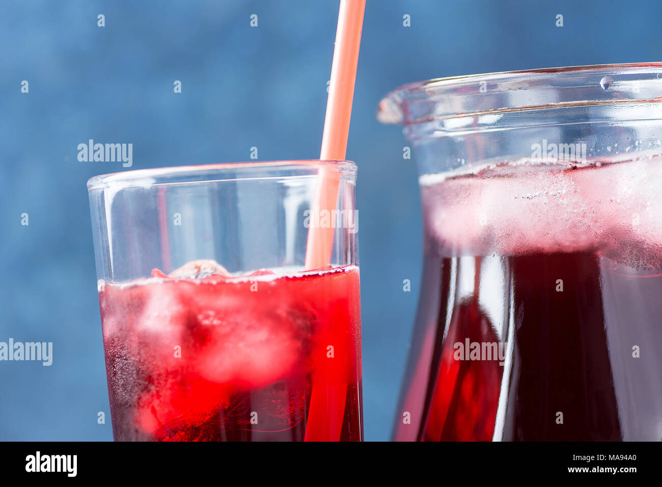 Healthy Refreshing Drink From Ice Hibiscus Tea and Red Berries and Fruits Juice in Pitcher and Tall Glass with Straw. Vitamins Superfoods Detox Hydrat Stock Photo