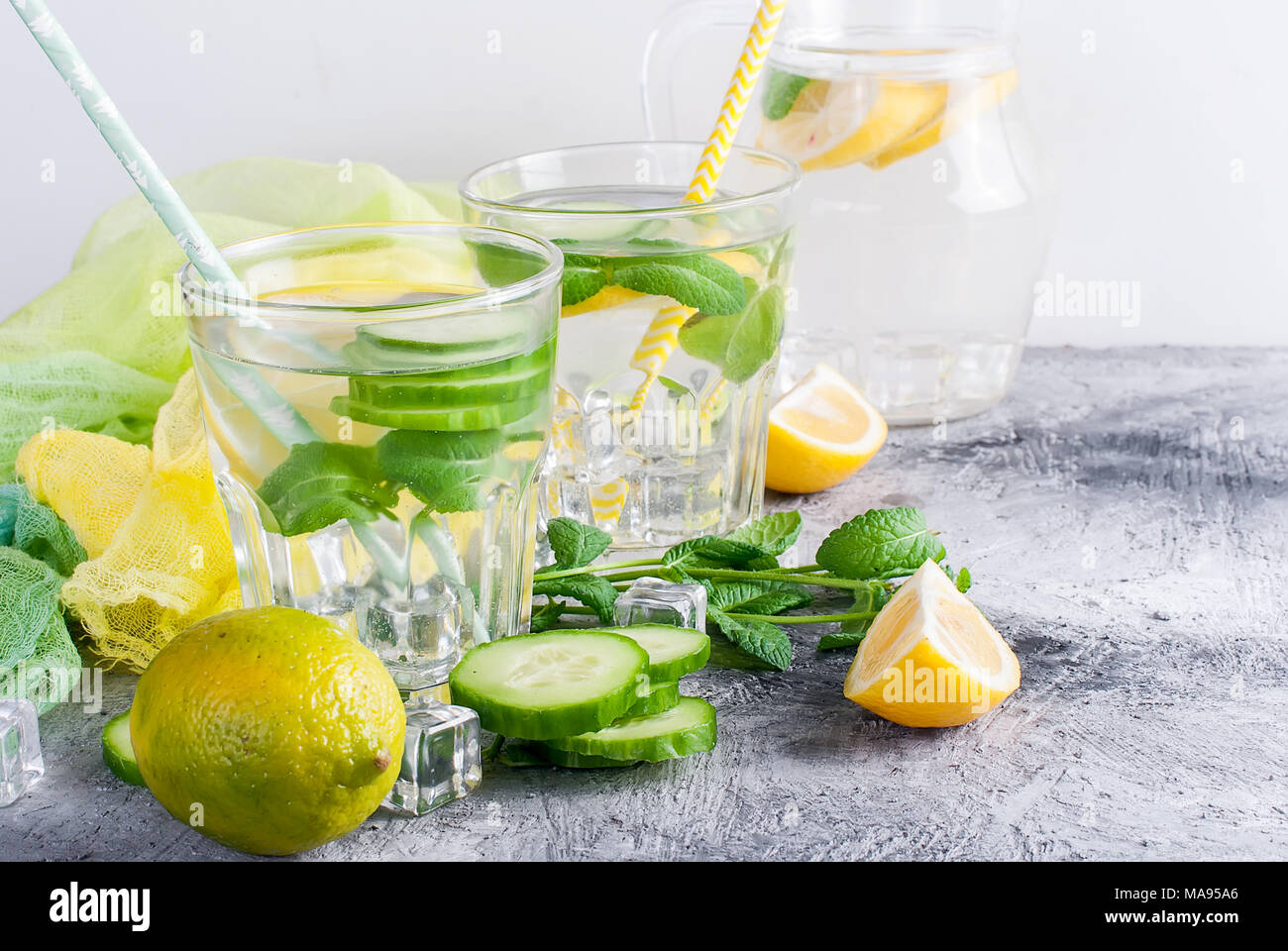 Citrus fruit and herbs infused sassi water for detox, healthy eating in  glasses and jug on over dark background Stock Photo