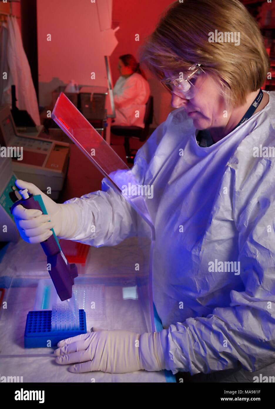 Photograph of the CDC microbiologist Susan Phillips working inside a laboratory with HIV samples, wearing protective gear, developing methods for rapid detection of HIV, and biologist Trudy Dobbs in the background, working in a Biological Safety Cabinet, 2007. Image courtesy CDC/Hsi Liu, James Gathany. () Stock Photo