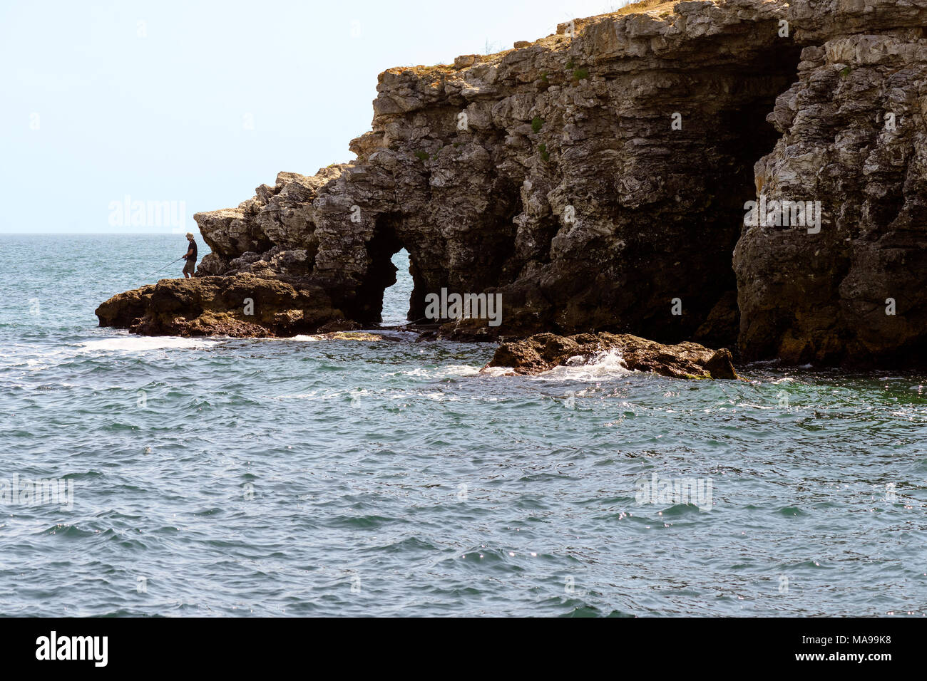 Tyulenovo, Bulgaria - July 20, 2017: Fisherman on the precipitous rocks of Kamen Bryag on the coast of Black Sea Stock Photo