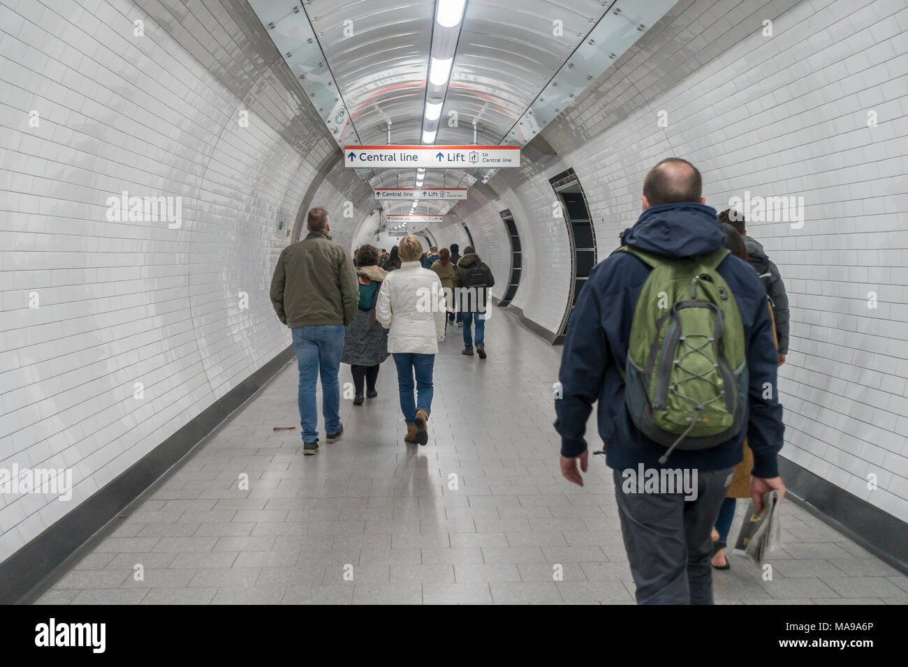 Passengers walk down a connecting tunnel towards the Central Line at a London Underground station. Stock Photo