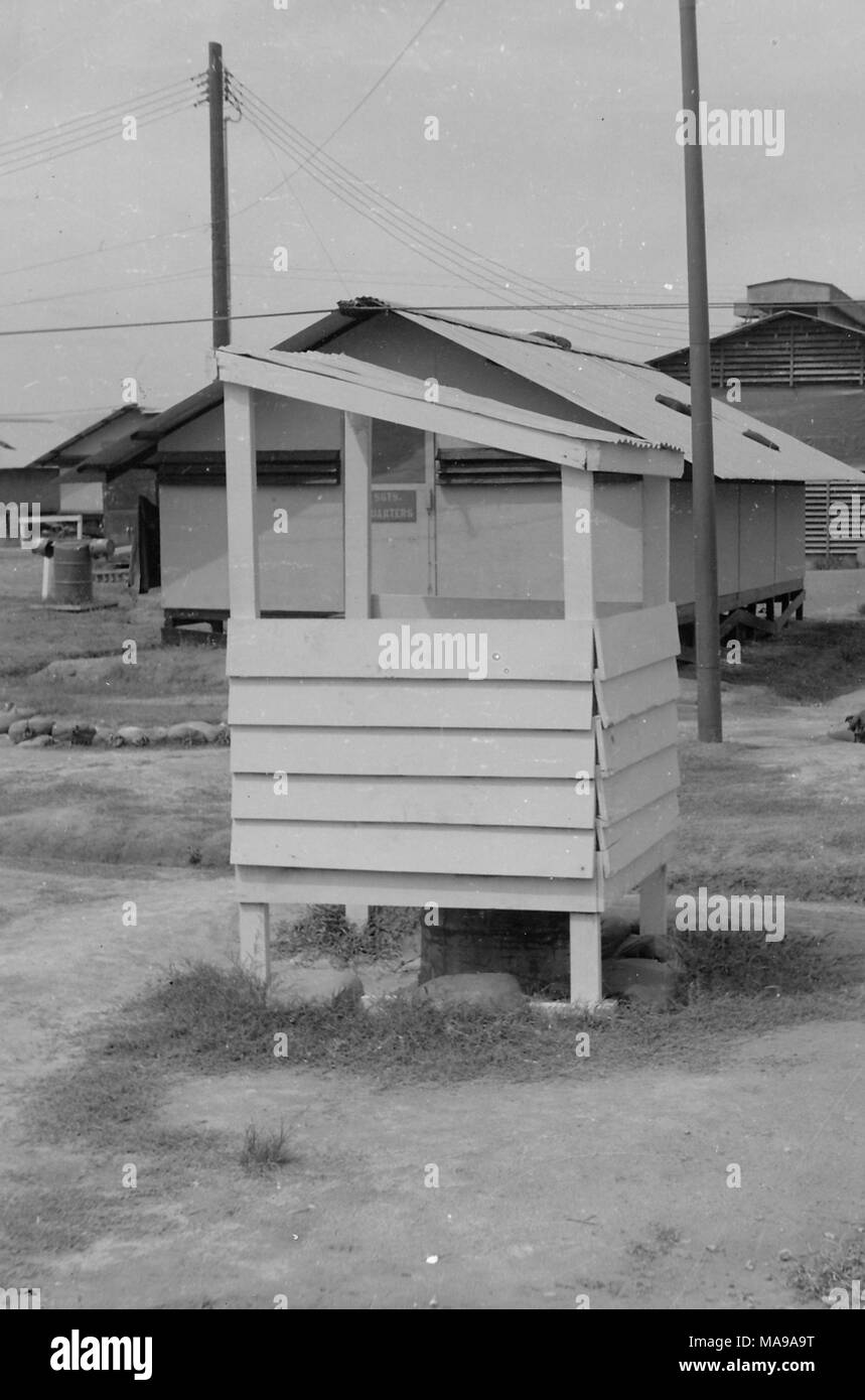 Black and white photograph showing several buildings, including a wooden guard-post in the foreground, sergeant's quarters in the midground, and several other barracks in the background, photographed in Vietnam during the Vietnam War (1955-1975), 1968. () Stock Photo