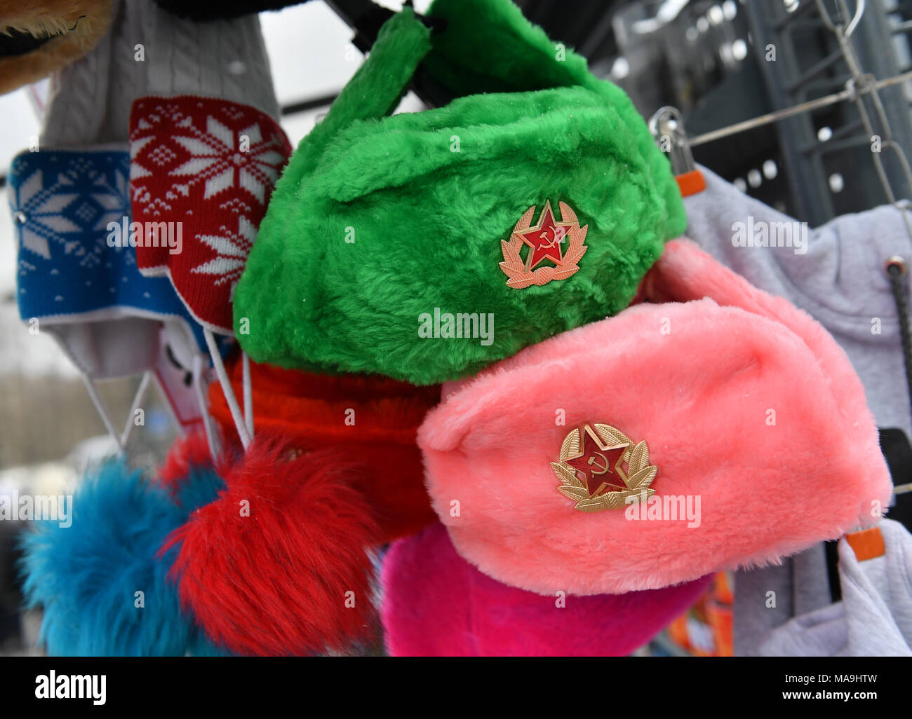 15 March 2018, Russia, St. Petersburg: A pink and a green czapka with the Soviet emblem hanging in a souvenir stand in St. Petersburg. Photo: Hendrik Schmidt/dpa-Zentralbild/ZB Stock Photo