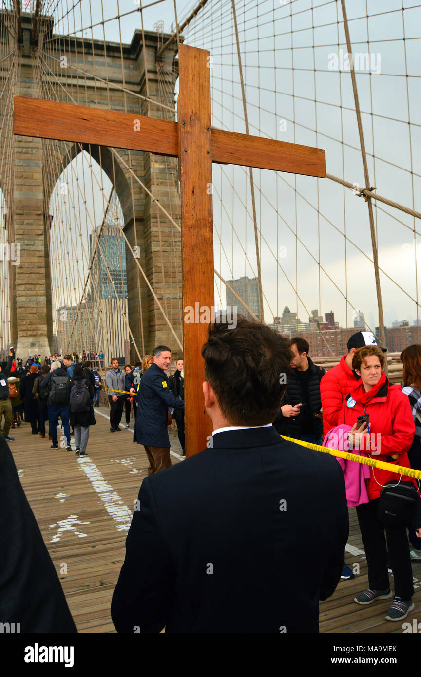 New York, NY, USA March 30, 2018 A young man carries a wooden cross across the Brooklyn Bridge, as part of a Good Friday procession in New York Credit: James Kirkikis/Alamy Live News Stock Photo