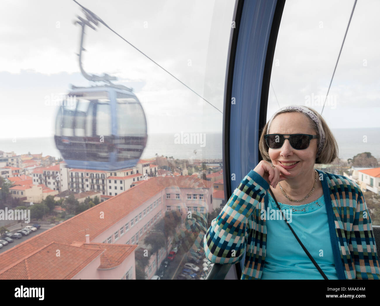 Senior adult woman riding in cable car over Funchal Stock Photo