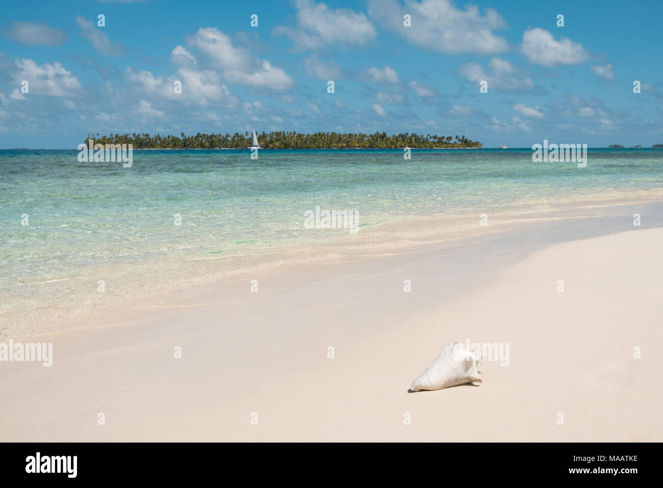 white sand beach, crystal clear water and palm tree island and sailing boat Stock Photo