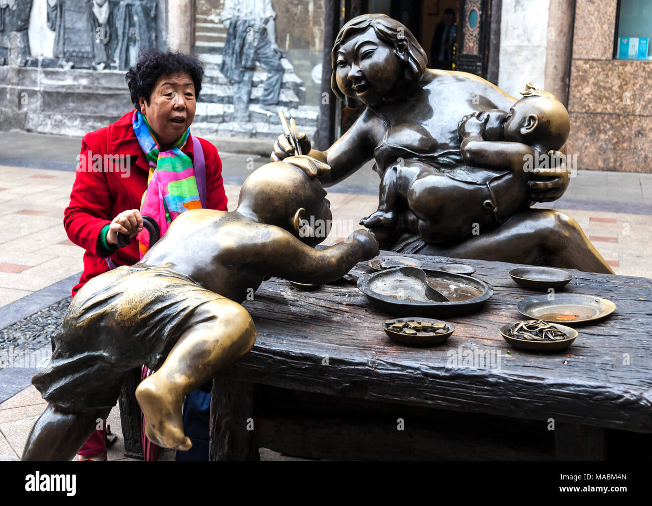 Chinese woman amazed at sculpture of mother and children in Chongquin Stock Photo