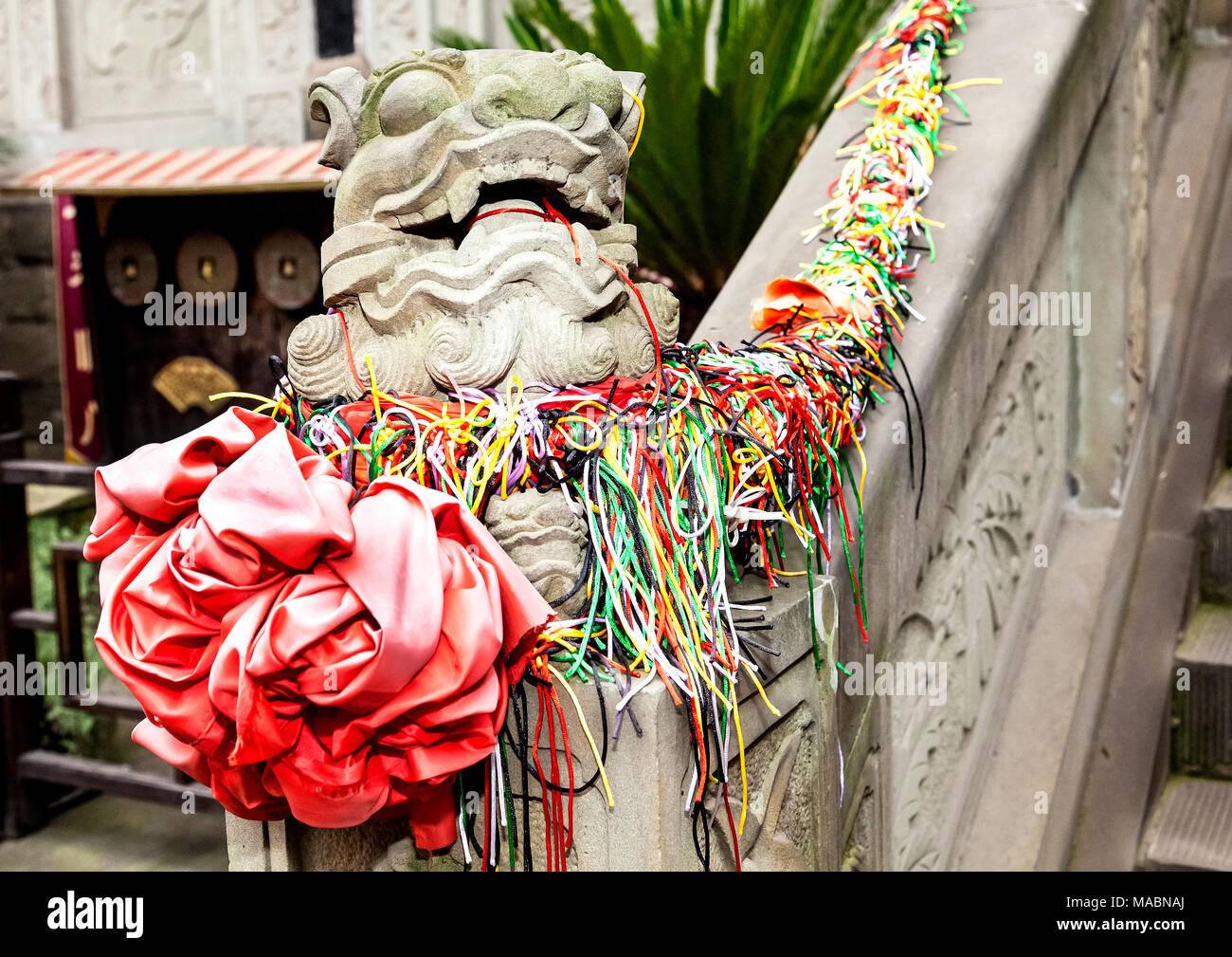 Tokens decorate concrete Chinese dragon statue at entrance to Emperor