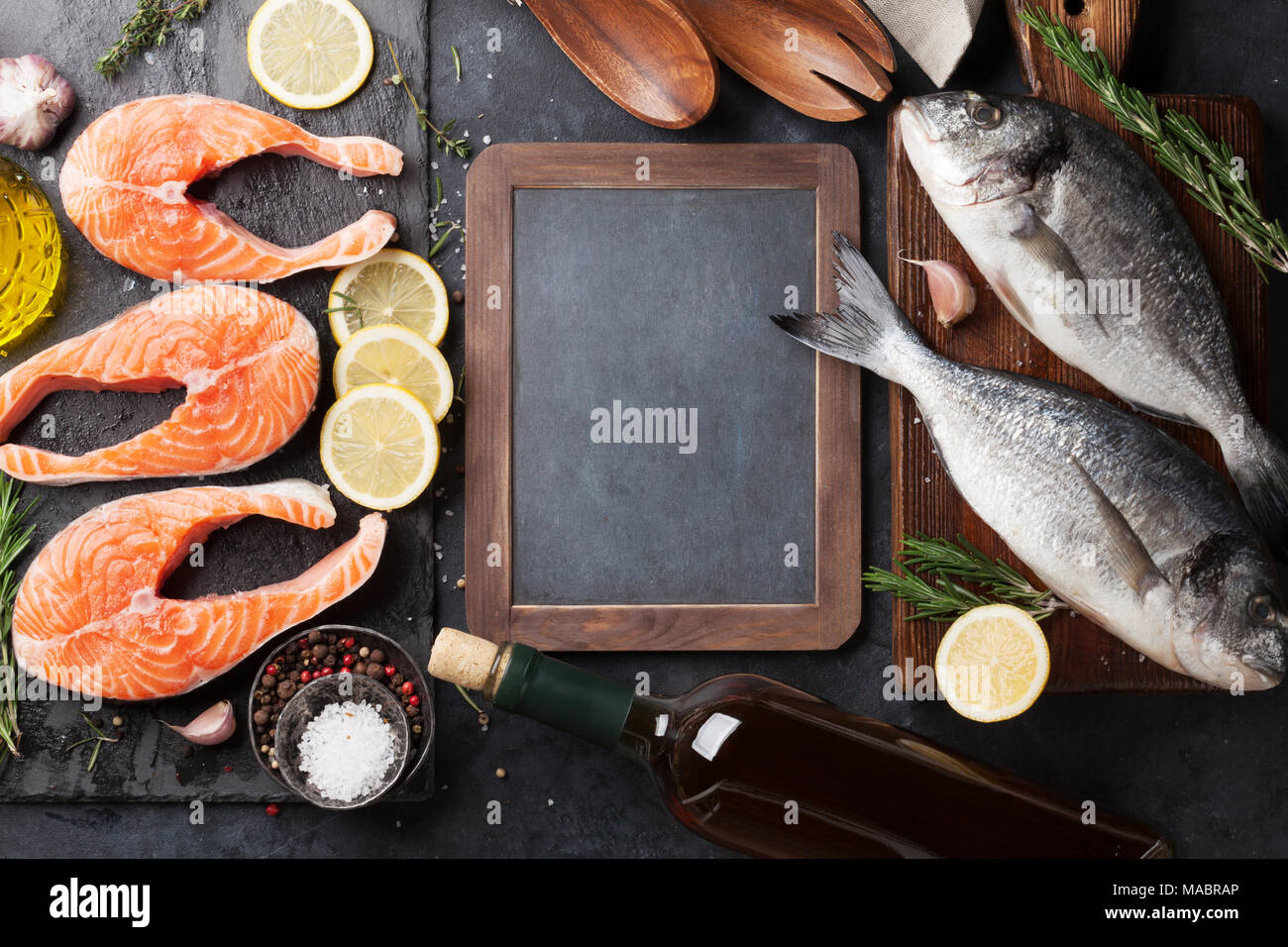 Raw salmon fish fillet and dorado with spices cooking on cutting board ...