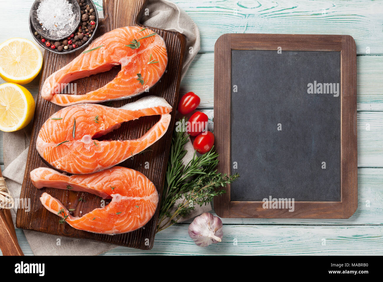 Raw salmon fish steaks with spices cooking on cutting board. Top view ...