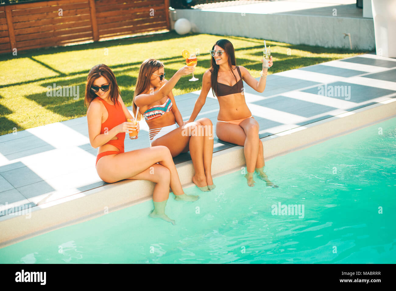 Young women having fun by the pool at hot summer day Stock Photo