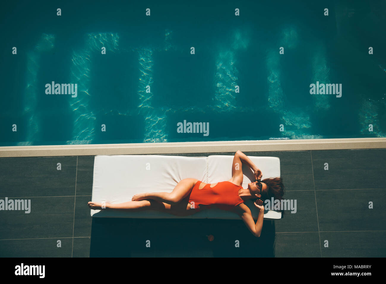 Top view at young slim beautiful woman in swimsuit sunbathing near swimming pool Stock Photo