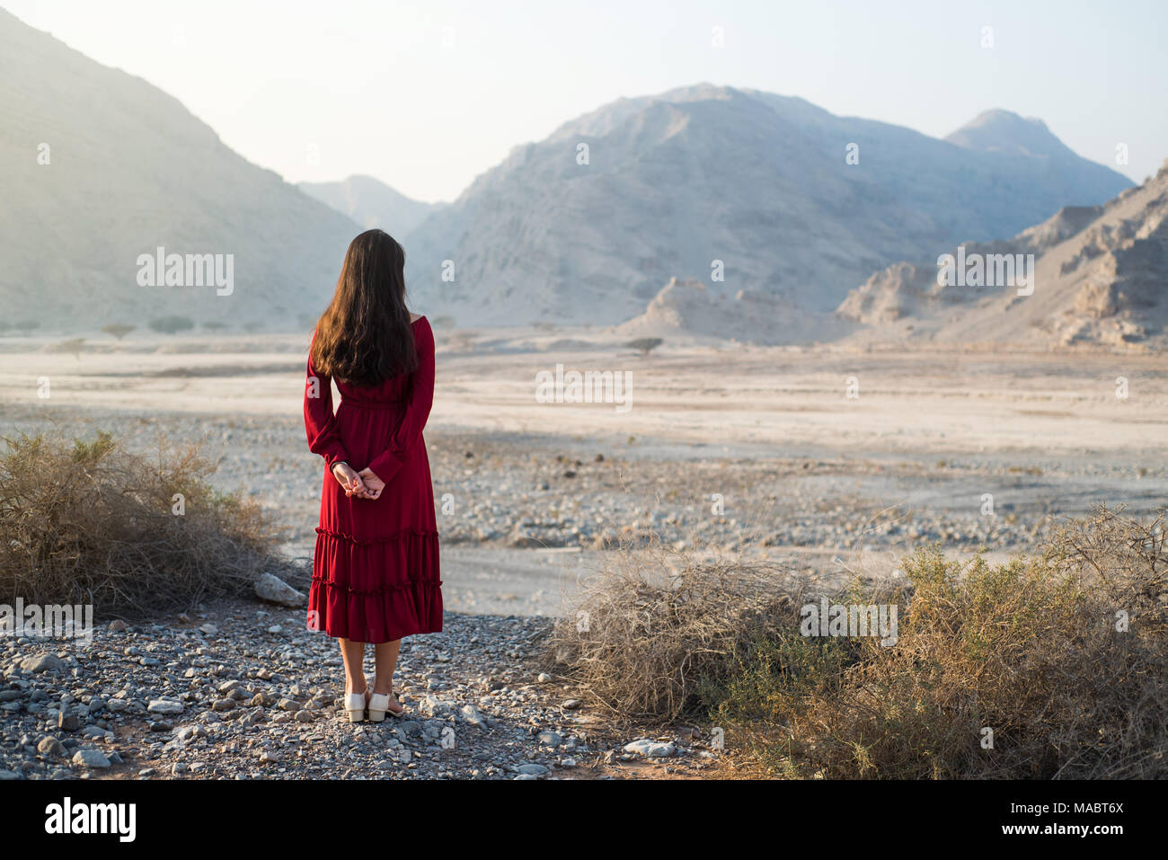 Woman enjoying dessert valley and mountain scenery wearing red dress Stock Photo