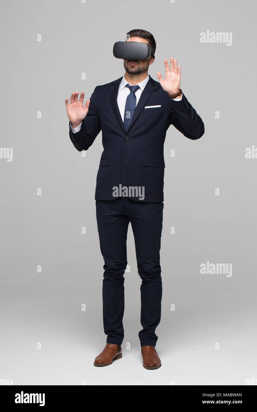 Stylish businessman in formal wear using VR glasses, touching imaginary virtual interface Stock Photo