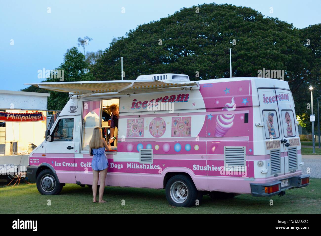 A blonde young lady buys ice cream from an ice cream van at riverway night market, Riverway
