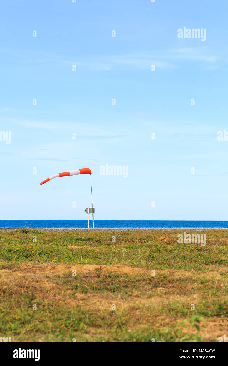 a wind force (windsock) against the dark sea and blue sky Stock Photo