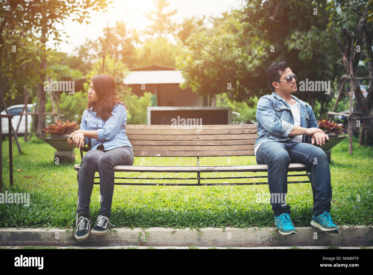 Displeased young couple sitting on bench in park, Couple lifestyle concept. Stock Photo