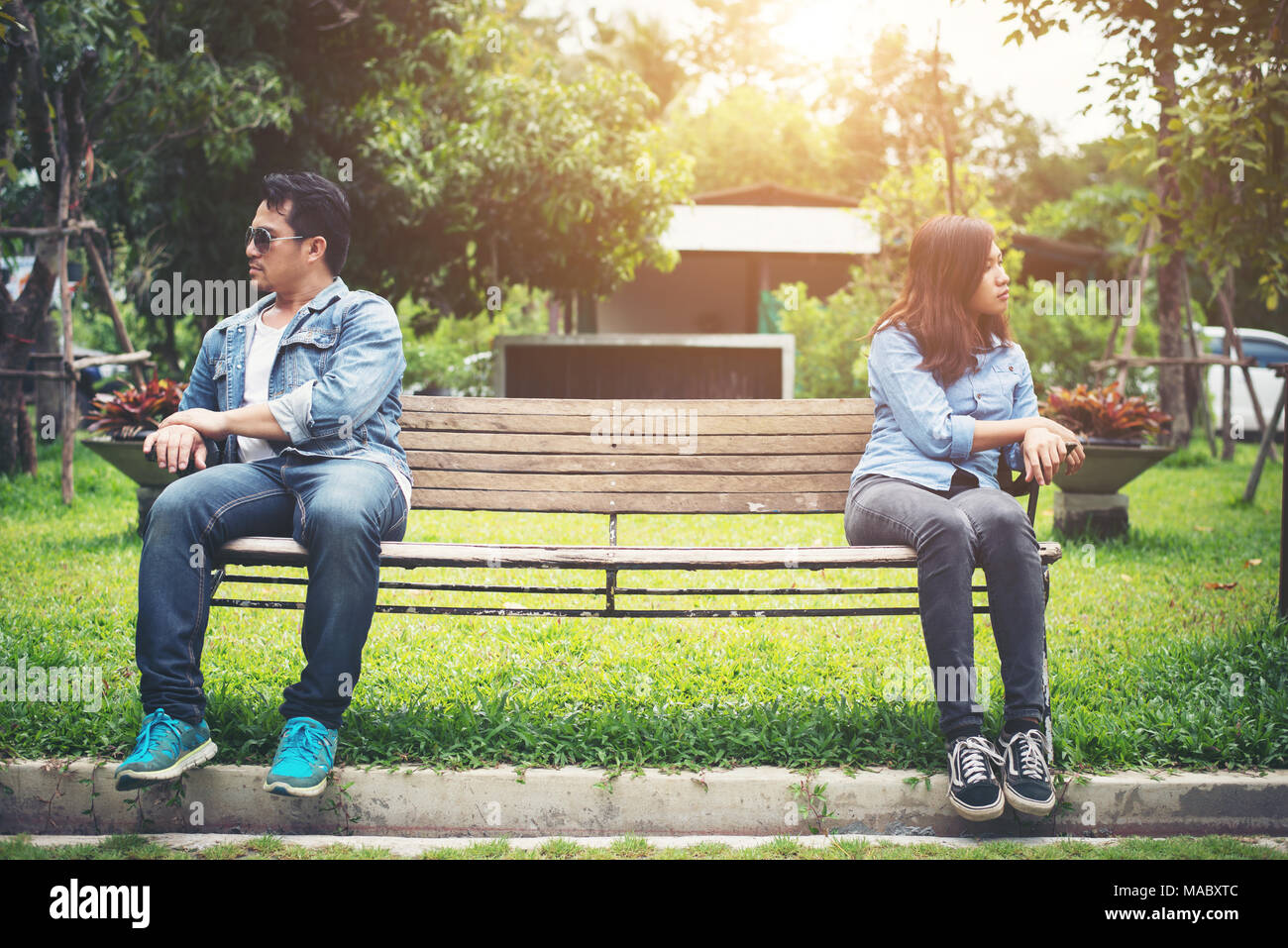Displeased young couple sitting on bench in park, Couple lifestyle concept. Stock Photo