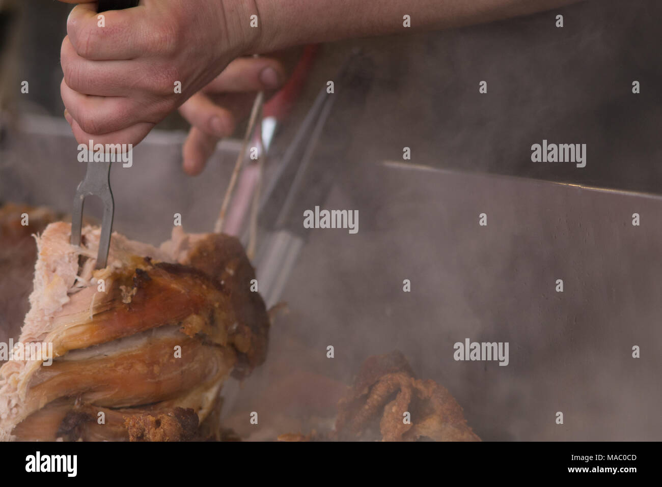 man carving pork joint with fork and knife at hog roast Stock Photo Alamy