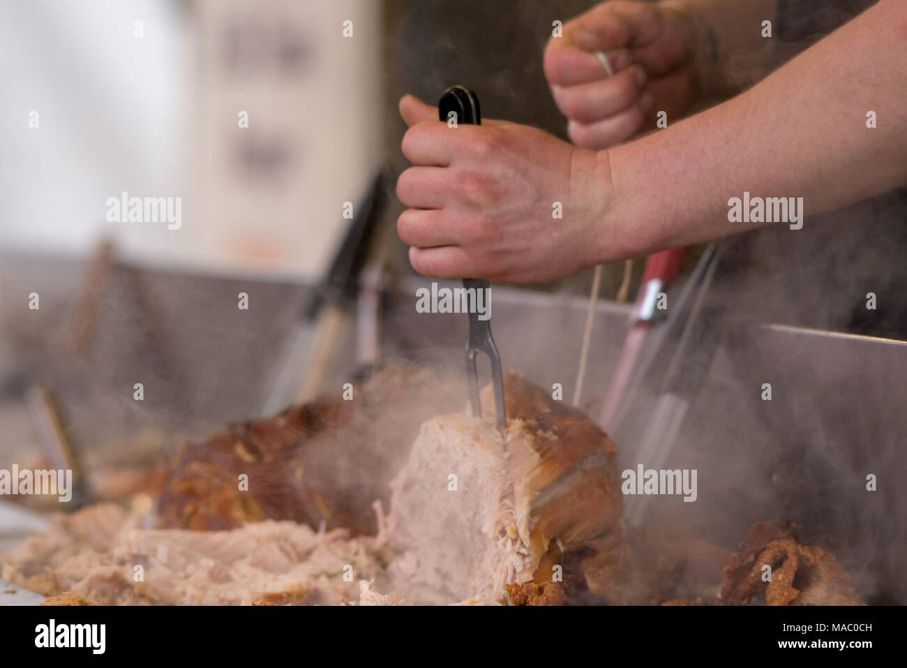 man carving pork joint with fork and knife at hog roast Stock Photo Alamy