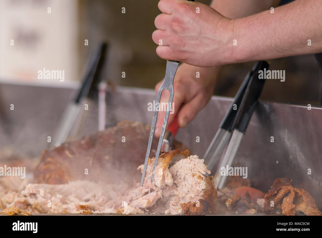 man carving pork joint with fork and knife at hog roast Stock Photo Alamy